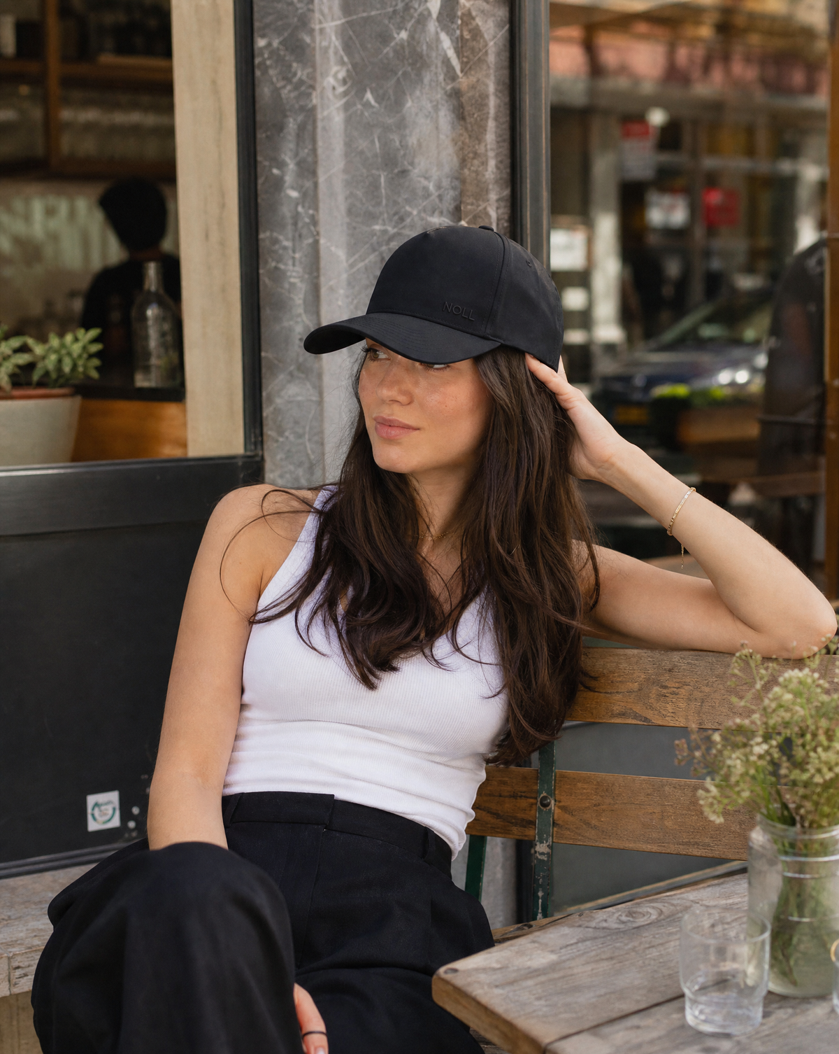 A woman wearing the matte black NOLL 01 hat, long hair loose