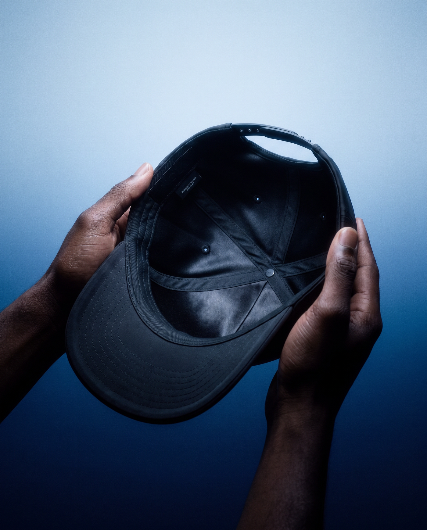Hands holding the NOLL 01 hat, showing the silk lining inside