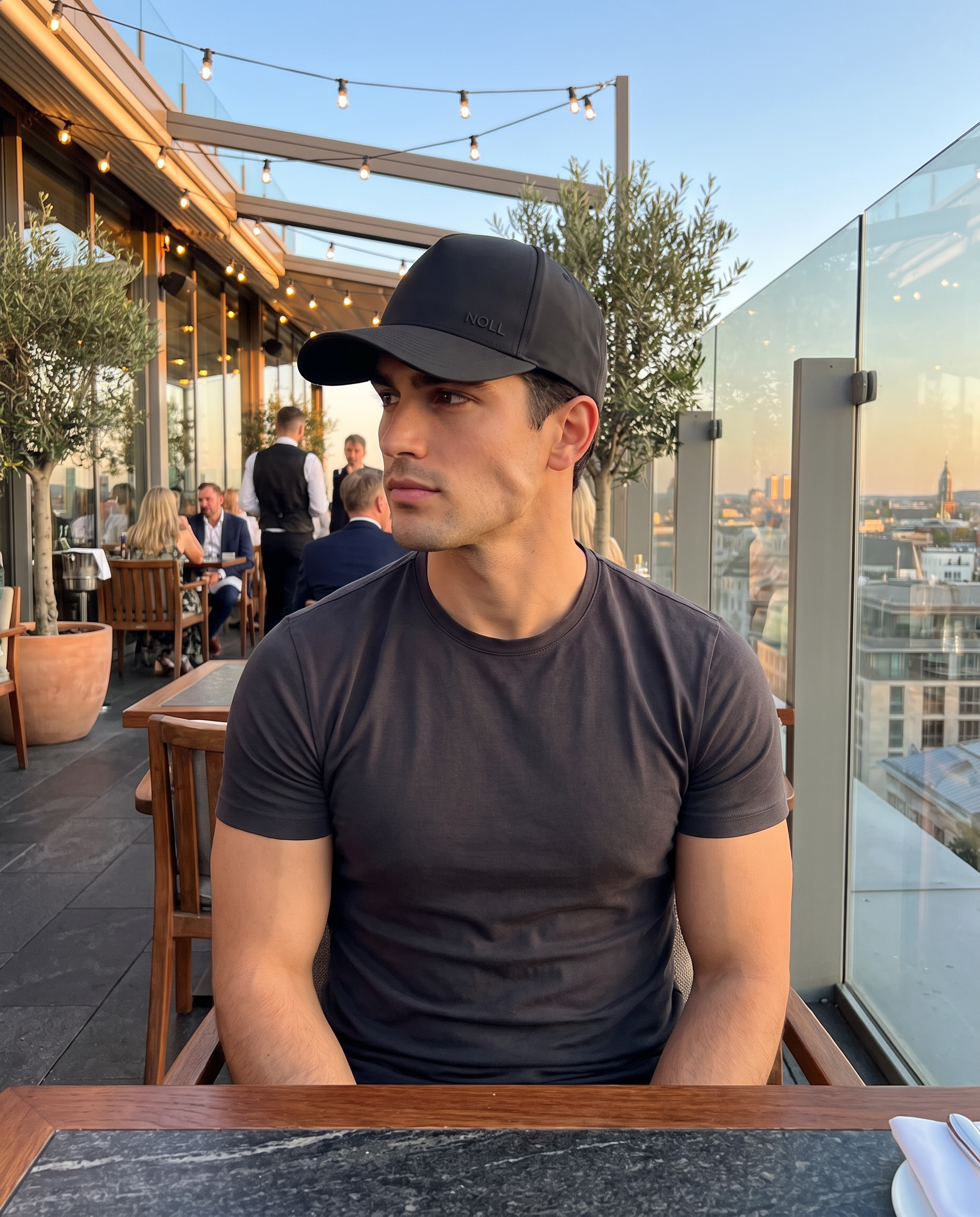 A man wearing the NOLL 01 hat at a rooftop terrace